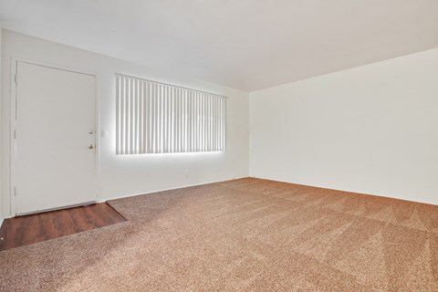 Living room with carpeted floors, wood style floors on the door entry area