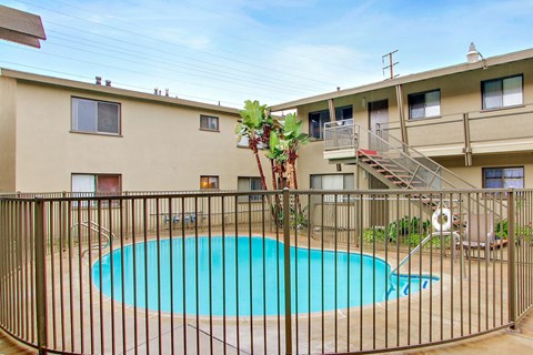 A pool surrounded by a black fence with a tree in the middle.