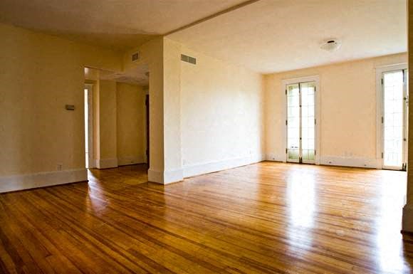 an empty living room with wooden floors and white walls
