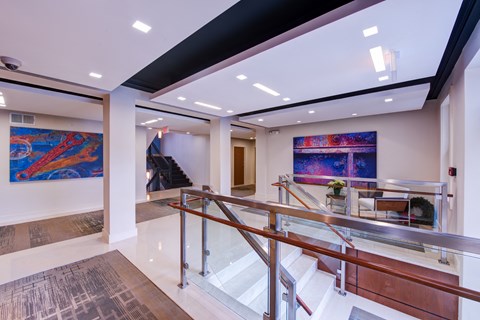 a large lobby with a staircase and paintings on the wall