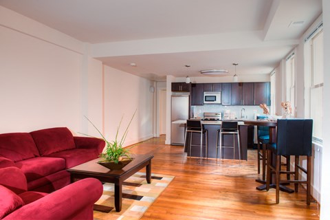 a living room with red couches and a kitchen with a bar