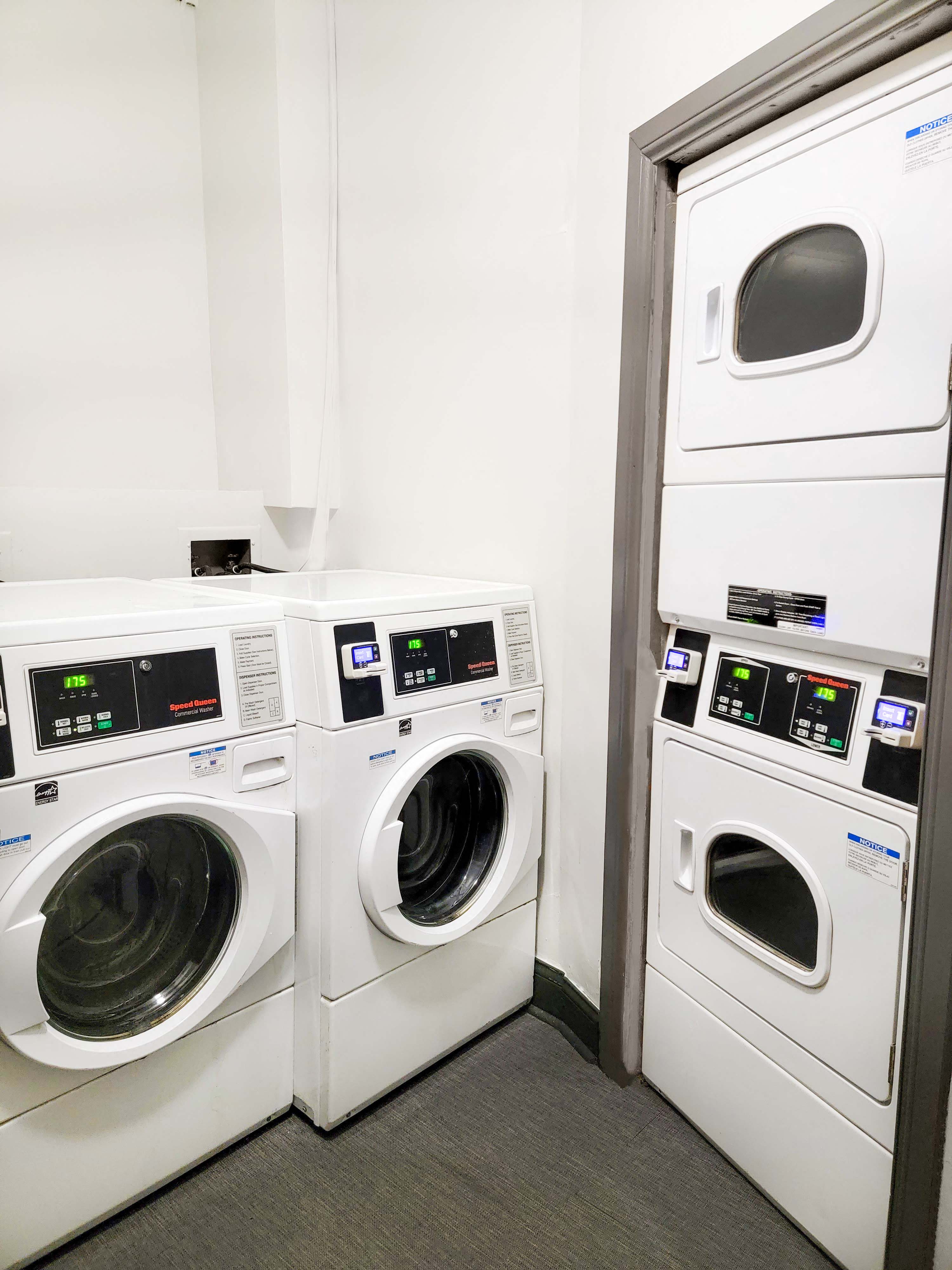 a row of washing machines and dryers in a laundry room