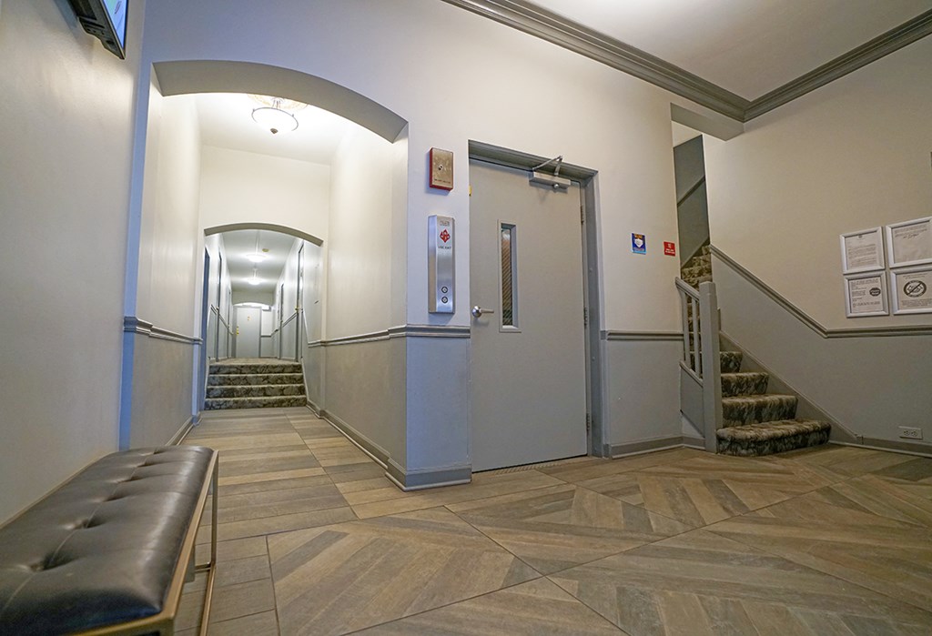 the lobby of a building with stairs and a bench