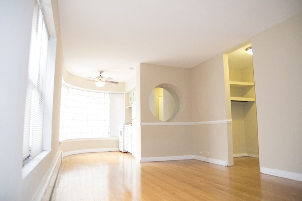an empty living room with a large window and wood floors