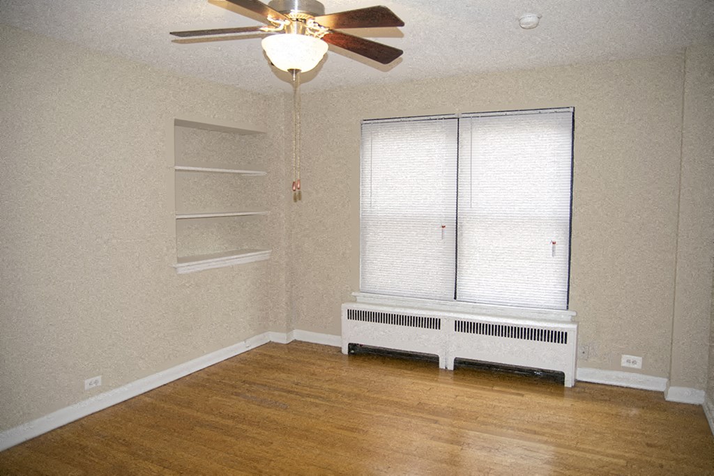 an empty living room with a ceiling fan and a window