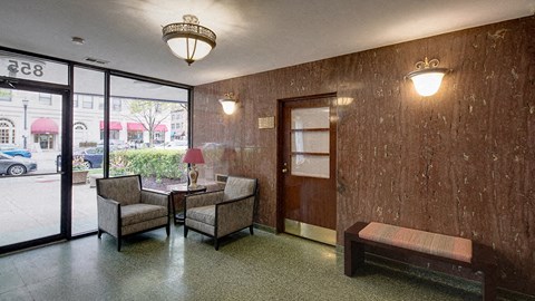 a lobby with chairs and a table and a glass door