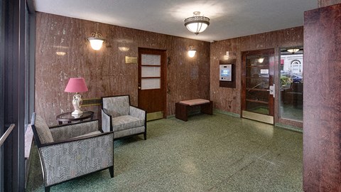 a lobby with two chairs and a lamp and a glass door