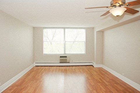 an empty living room with a ceiling fan and a window