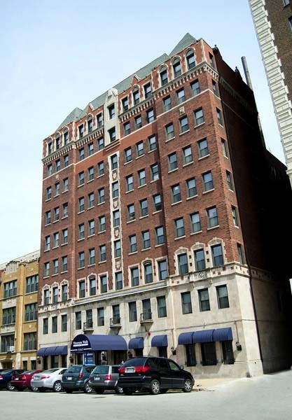 A tall red brick building with many windows sits next to a shorter tan building.