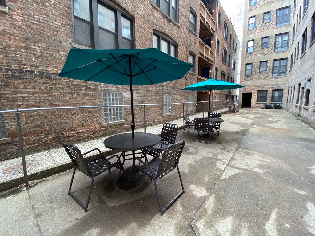 A patio with a table and chairs under an umbrella.