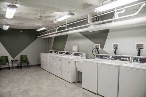 a group of washers and dryers in a room with a green chair