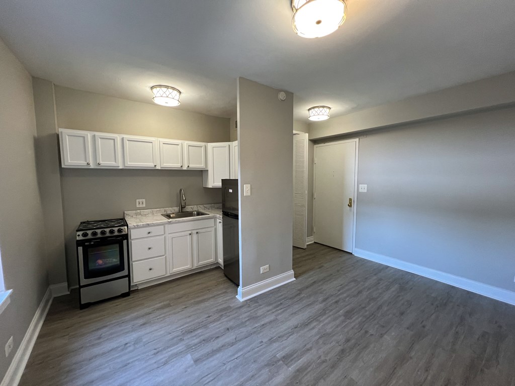 a kitchen and living room with white cabinets and stainless steel appliances
