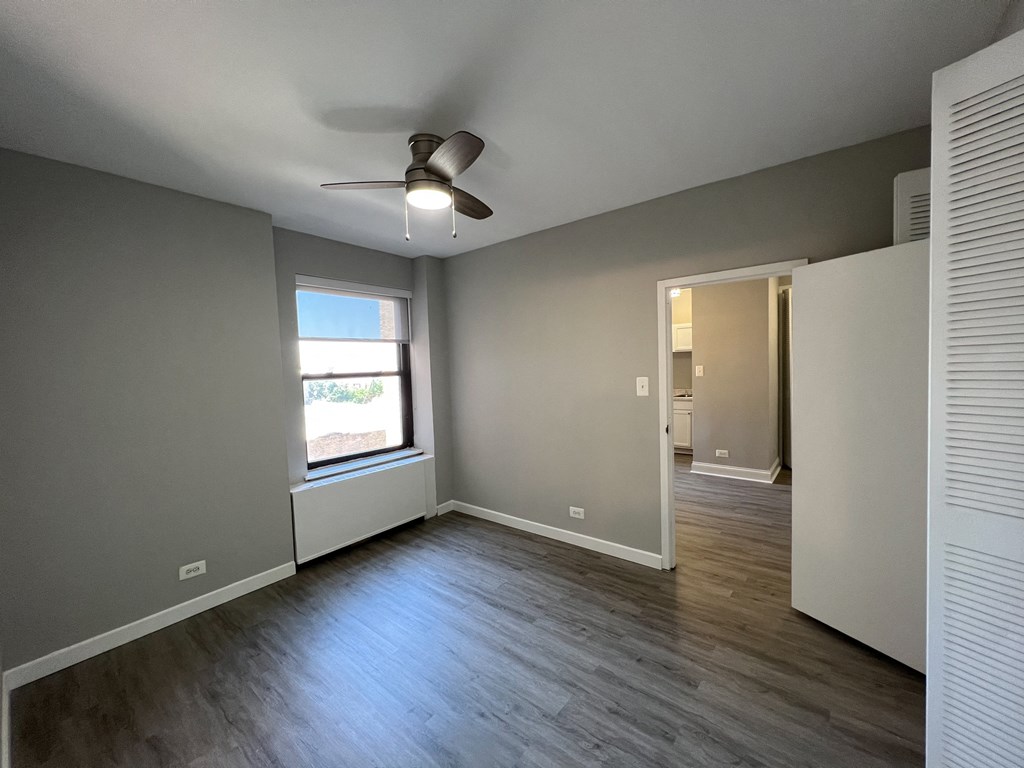 an empty living room with a window and a ceiling fan