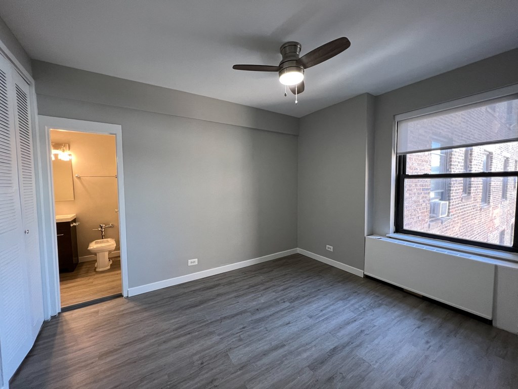 an empty living room with a ceiling fan and a large window