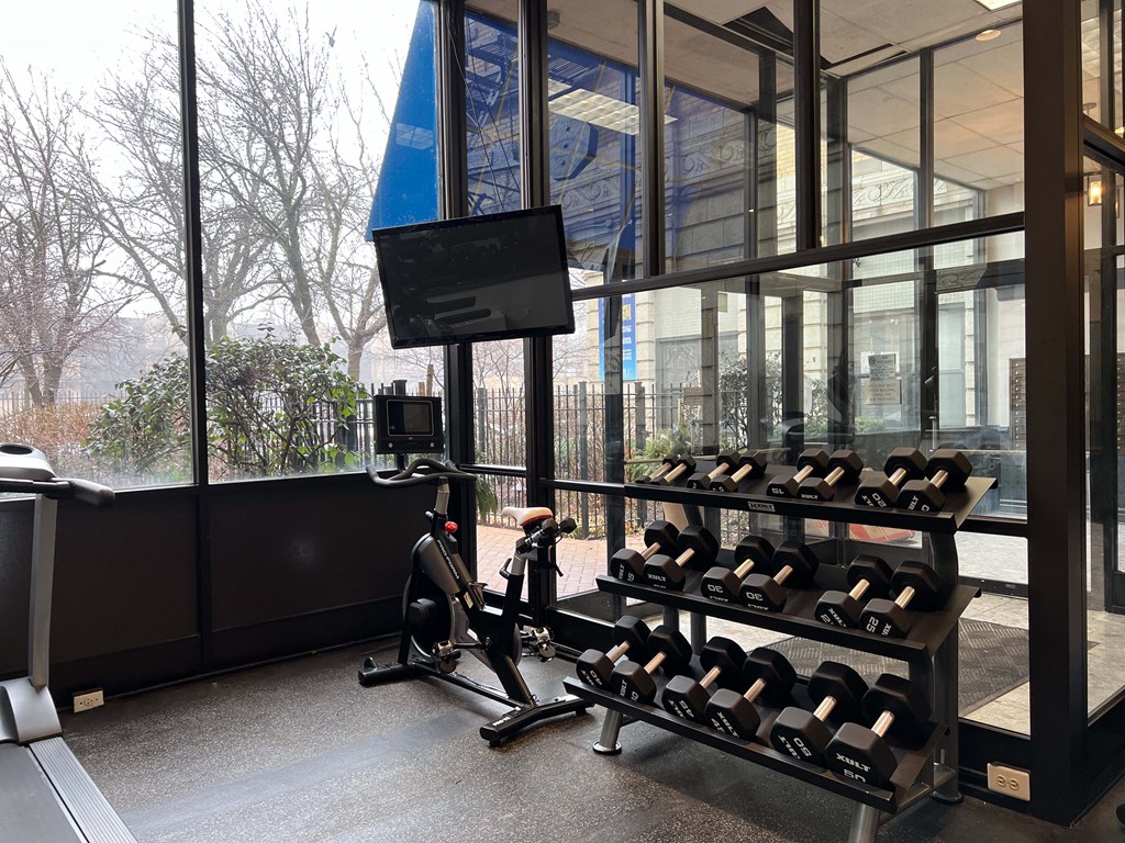 a gym with weights and a tv in front of a window