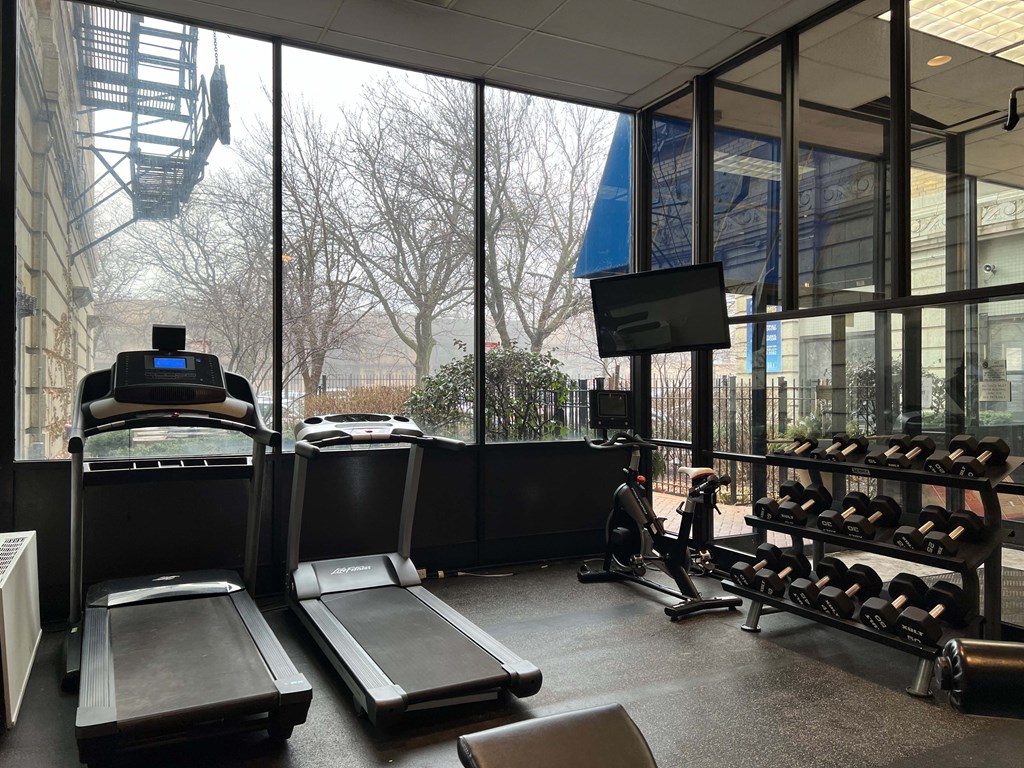 a gym with weights and a view of a building through the windows