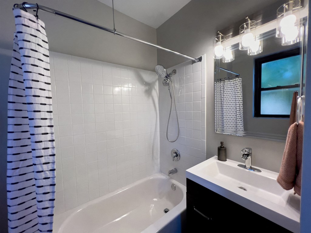 a bathroom with a white tub and shower and a sink