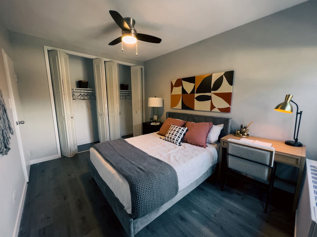 a bedroom with a bed and a desk and a ceiling fan