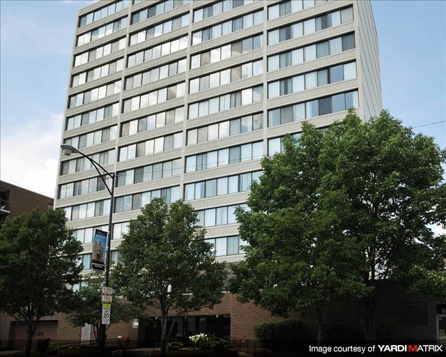 A tall building with many windows is surrounded by trees.
