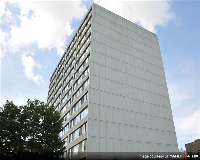 A tall building with a lot of windows and a tree in front.