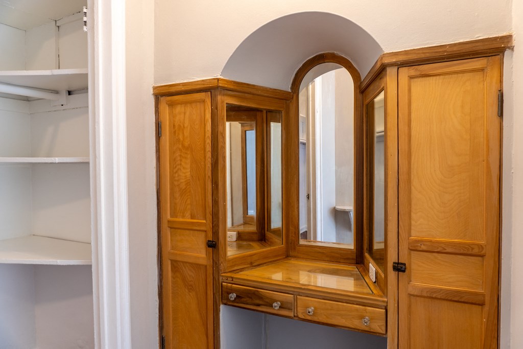 an empty wooden wardrobe in a room with an open door