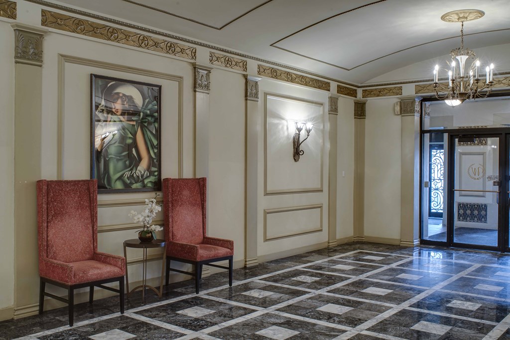 a lobby with two red chairs and a chandelier