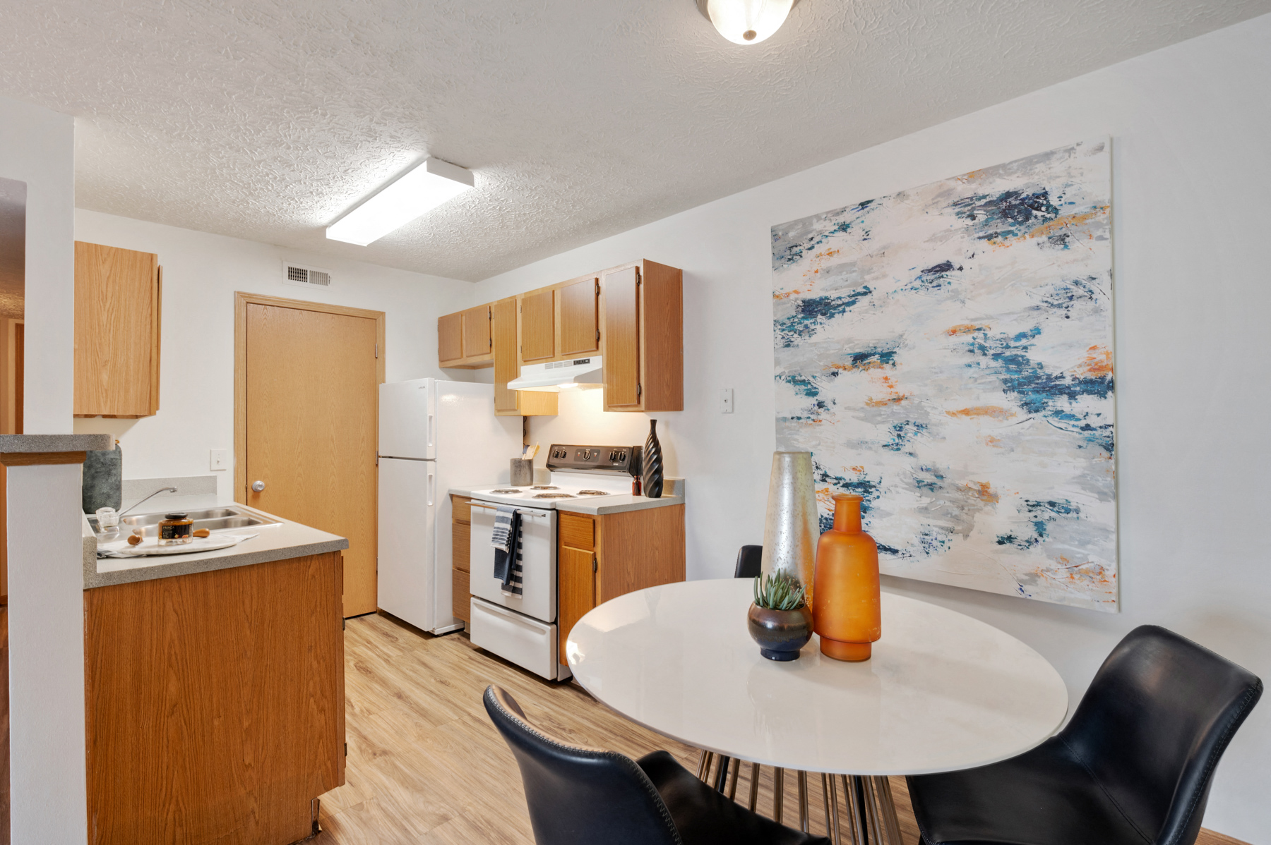 A kitchen with a table and chairs and a painting on the wall.