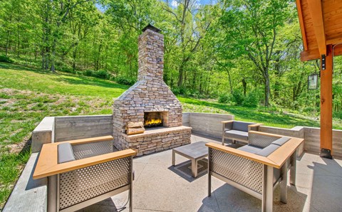 a backyard patio with a stone fireplace and tables