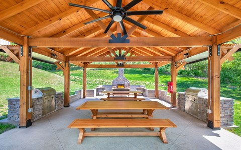 a covered patio with picnic tables and a grill