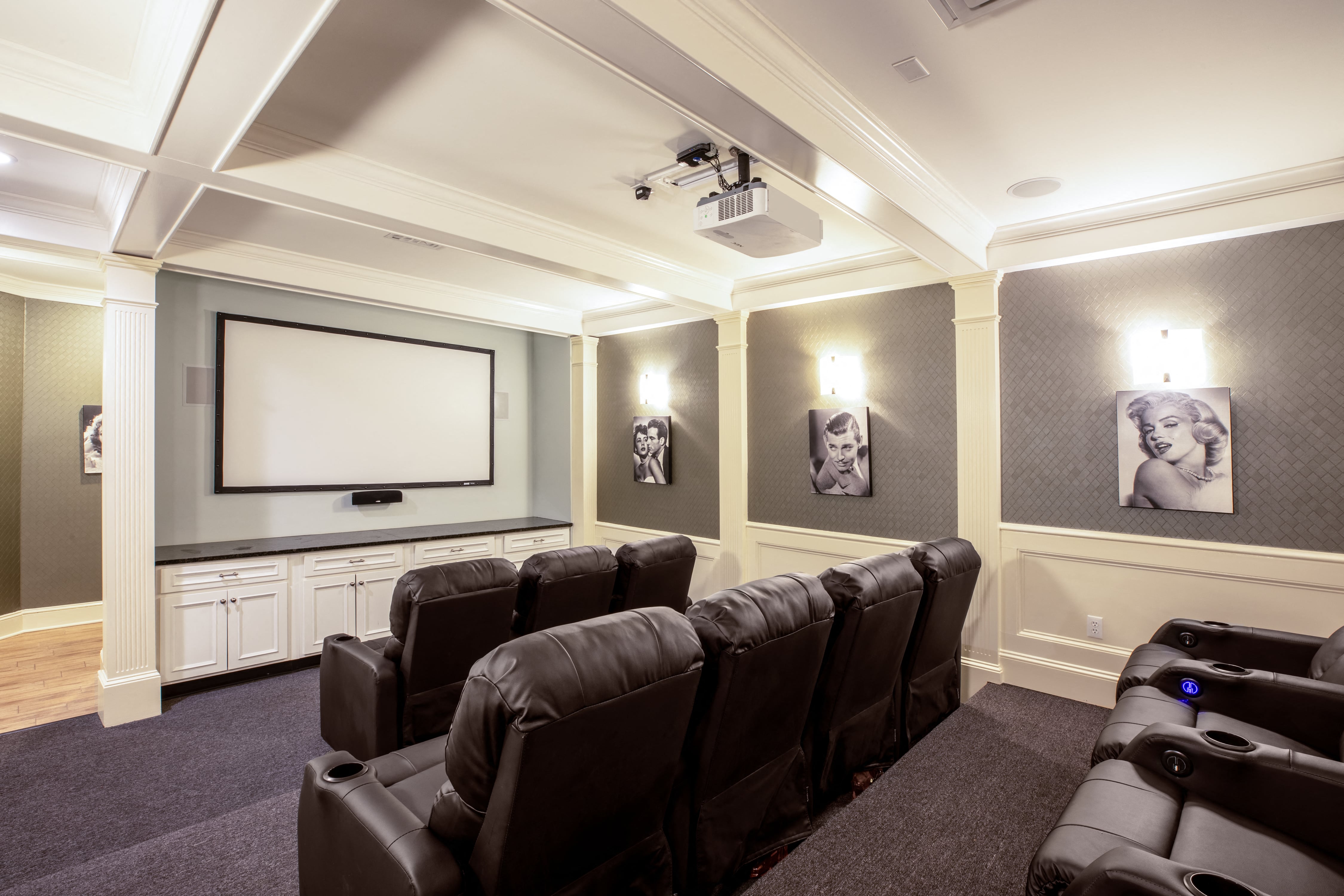 a home theater room with a projector screen and leather chairs