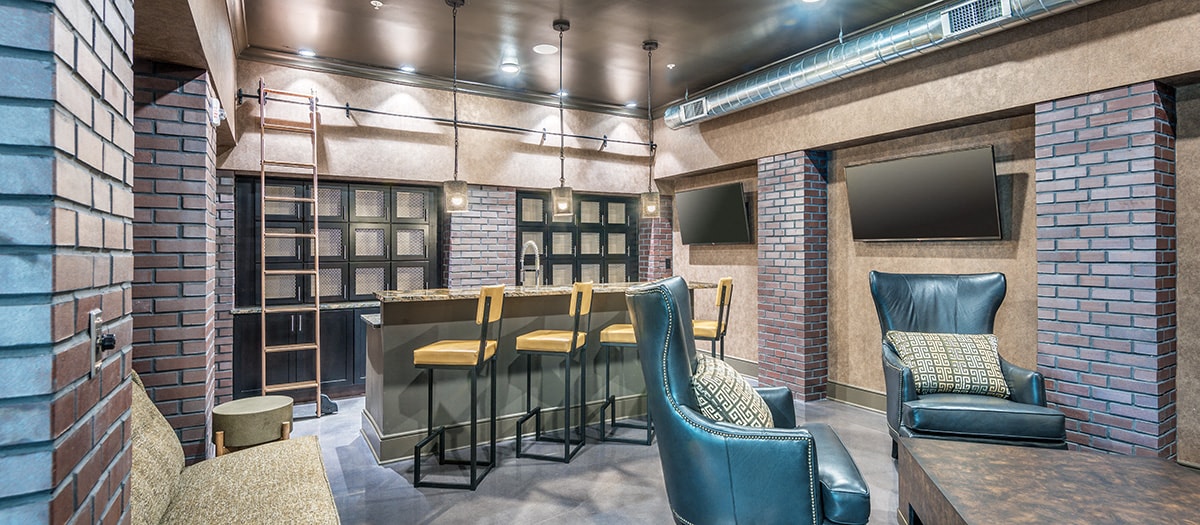 a bar area in a room with chairs and a television
