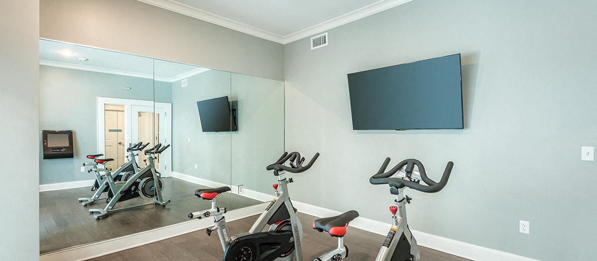 a gym with exercise equipment and a tv on the wall