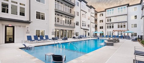 a swimming pool with chairs and umbrellas in front of a building