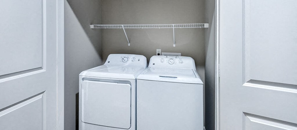two white washers and dryers in a white closet