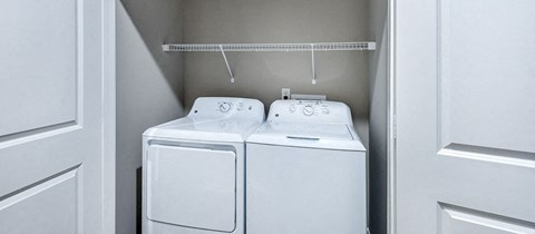 two white washers and dryers in a white closet