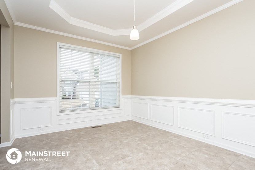 an empty dining room with white walls and a window