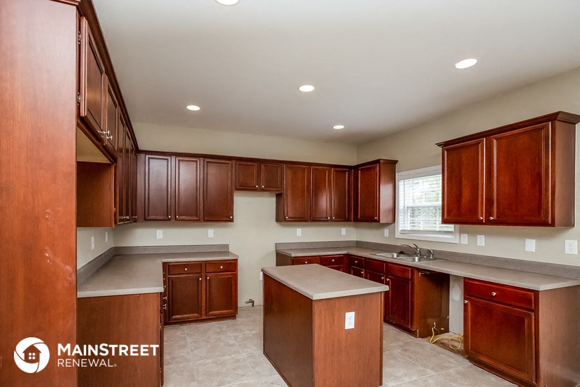 a kitchen with wooden cabinets and white counter tops and a sink