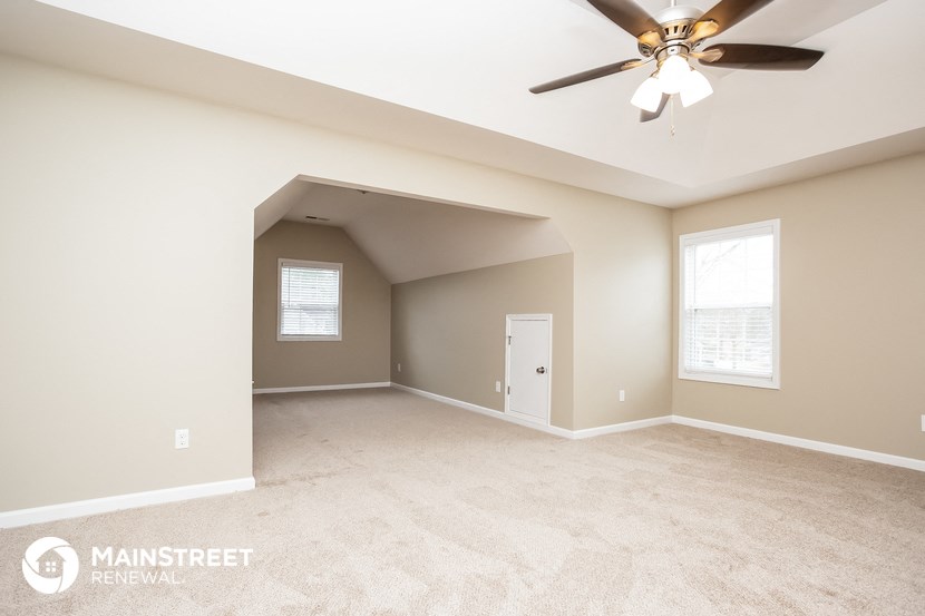 the spacious living room with carpet and ceiling fan