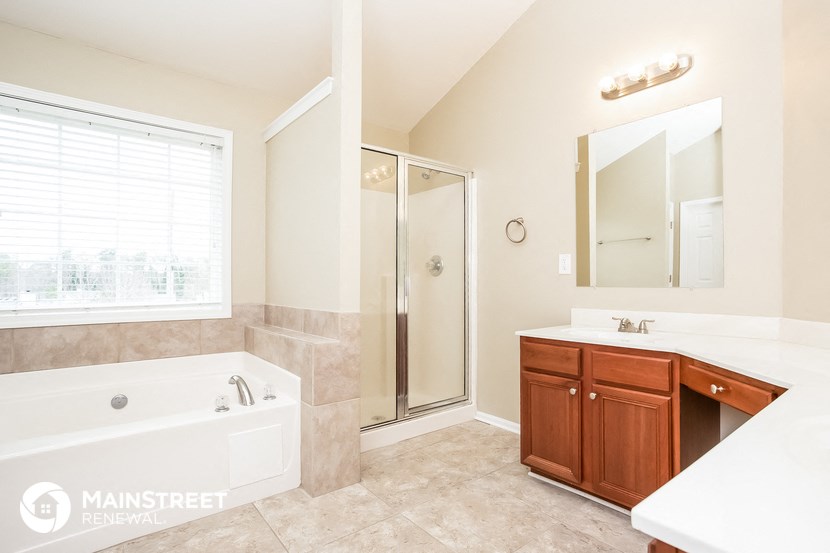 a bathroom with a tub and a shower and a sink and a mirror