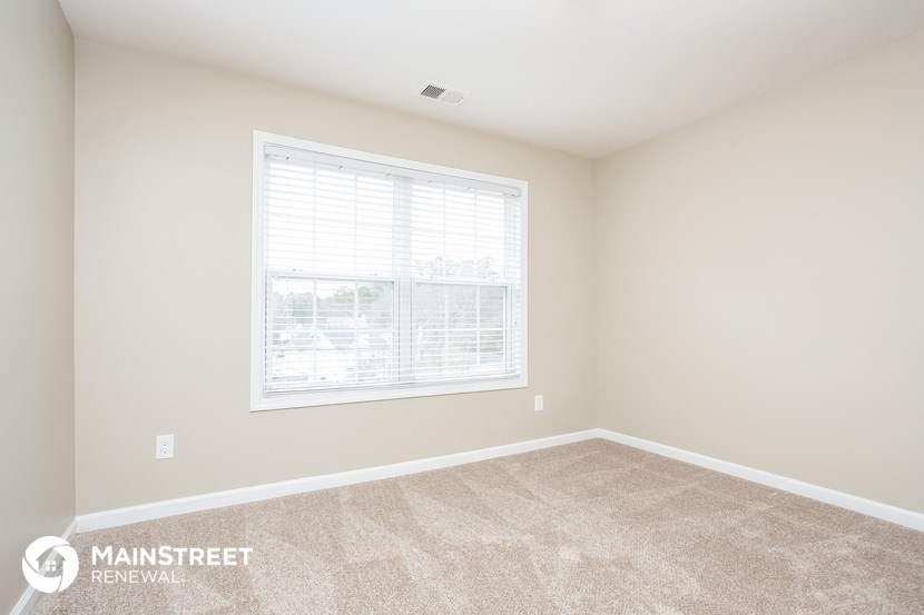 a spacious room with a large window and carpeted flooring