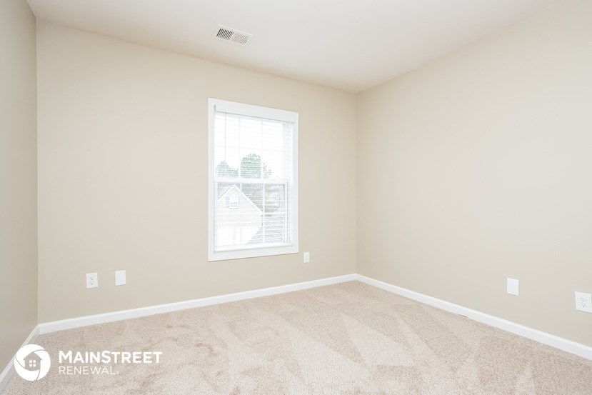 a spacious room with carpeted flooring and a window