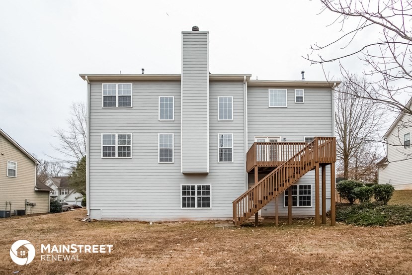 the back of a white house with a deck and a