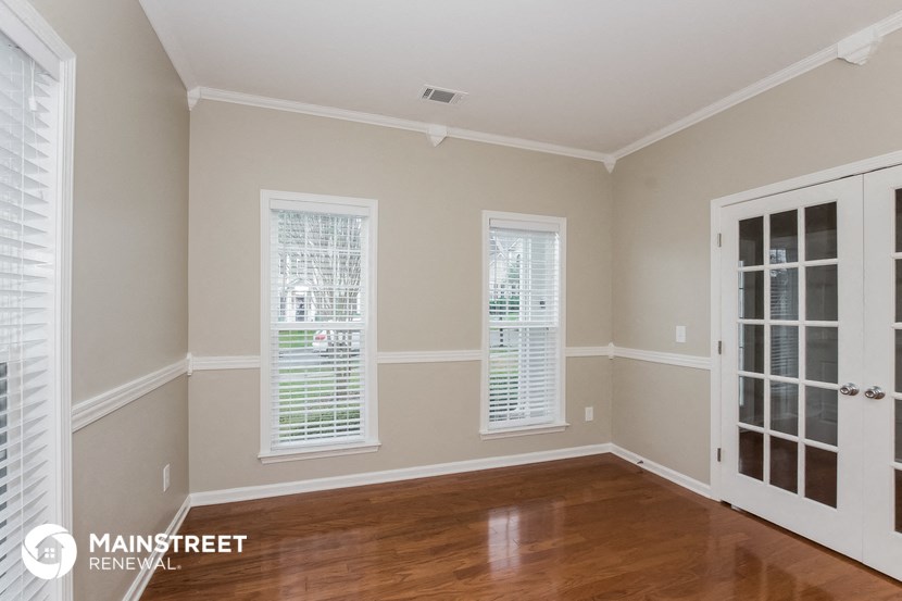 the living room of a home with wood floors and a door to the dining room