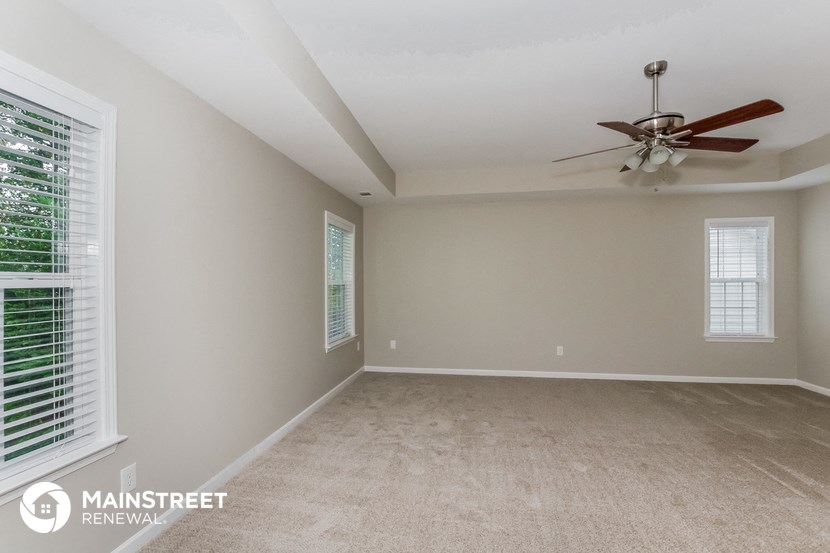 the spacious living room with ceiling fan and window