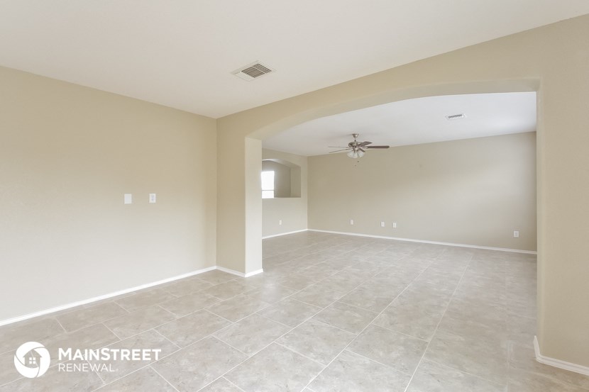 an empty living room with tile flooring and a ceiling fan