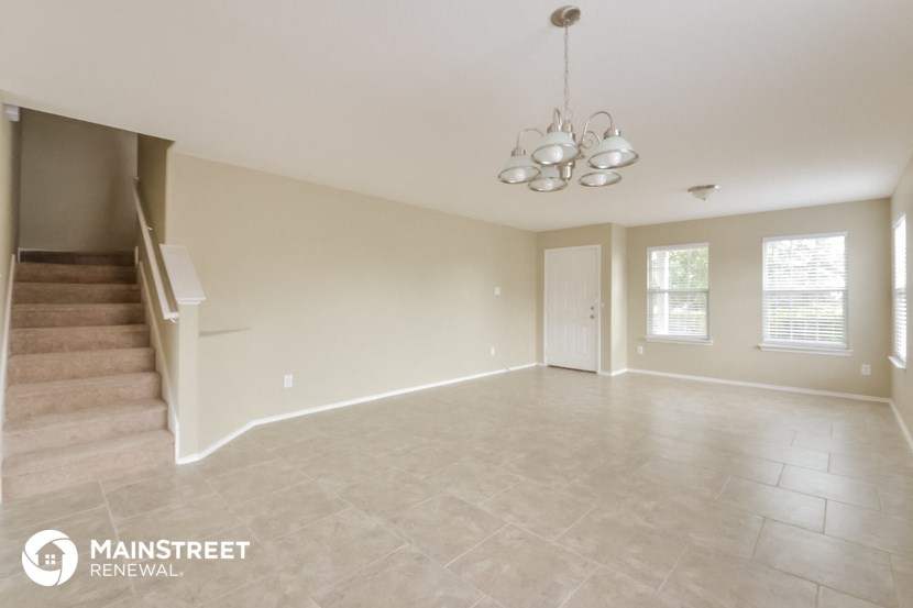 an empty living room with stairs and a chandelier