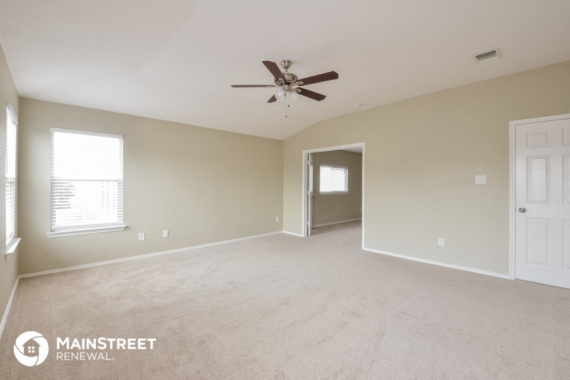 the spacious living room with ceiling fan and carpeting