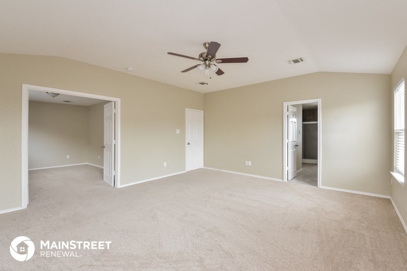 an empty living room with a ceiling fan