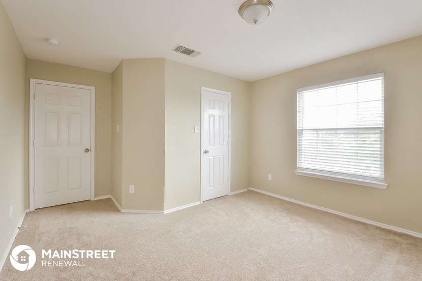 a bedroom with two doors and a window and a carpeted floor