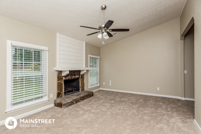an empty living room with a fireplace and a ceiling fan